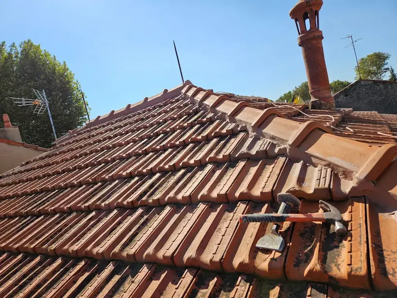 Toiture en tuiles anciennes avec souche de cheminée en terre cuite, avant intervention